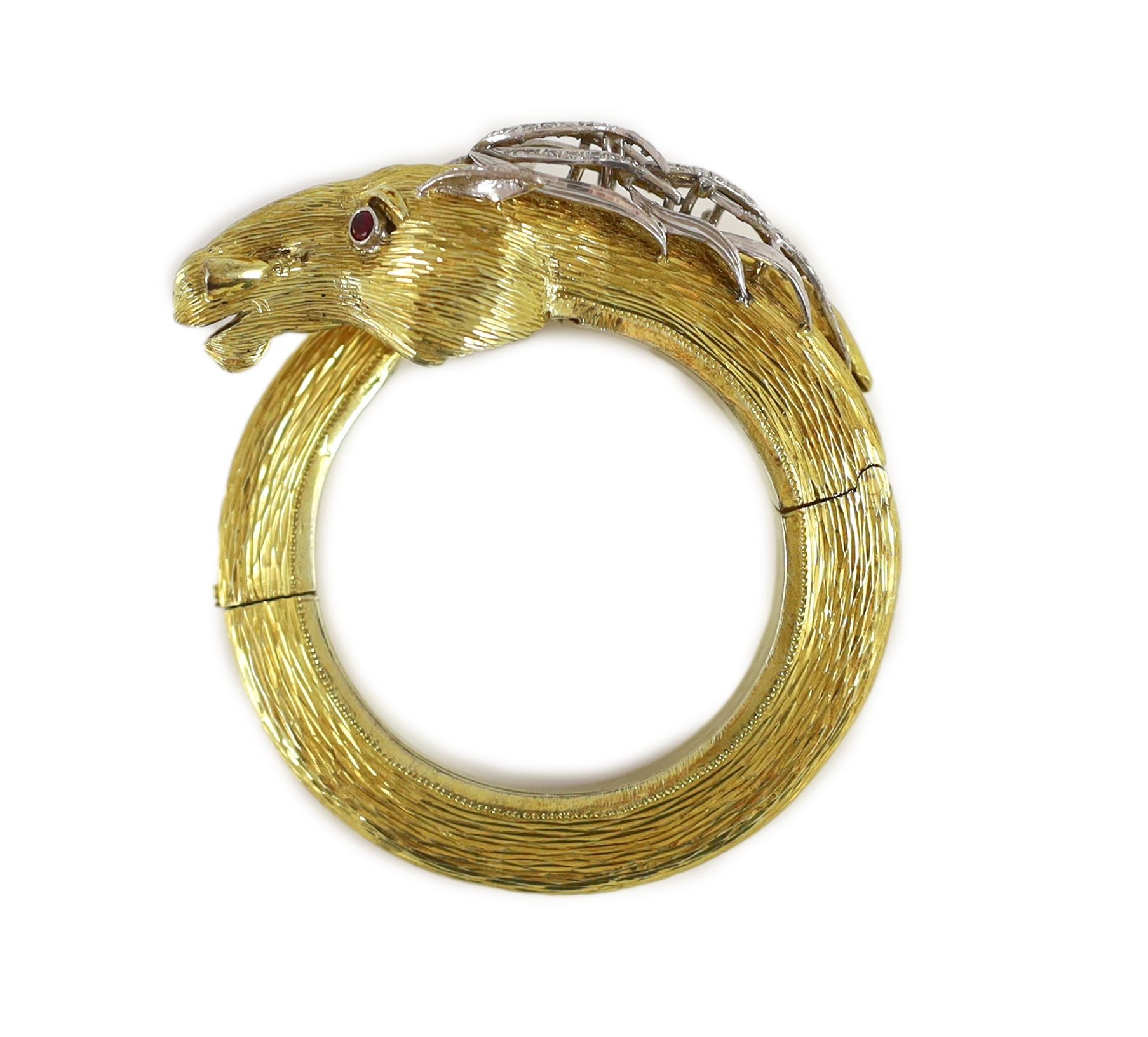 A 20th century Continental textured 14k gold, ruby and diamond set hinged bangle, modelled as the head and tail of a horse